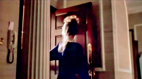 Blonde woman in blue top opening door, teasing glance over shoulder