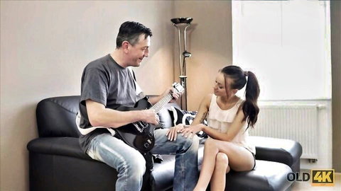 Old man plays guitar seducing young Asian teen girl on couch in old young taboo scene