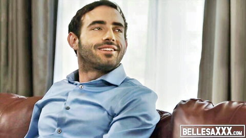 Handsome bearded man in blue shirt smiling seductively on leather couch