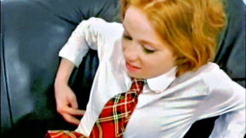 Freckled redhead schoolgirl in white blouse plaid tie and skirt teasing on leather couch