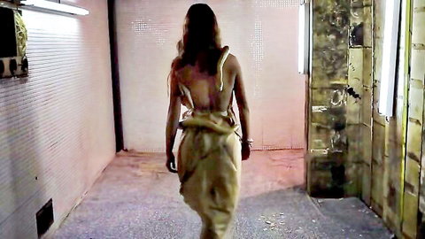 Erotic nude babe in minimal beige straps walking away exposing bare ass in gritty industrial room