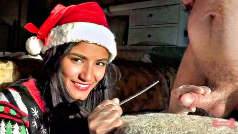 Smiling Santa hat mistress holds metal rod to slave's erect cock urethra