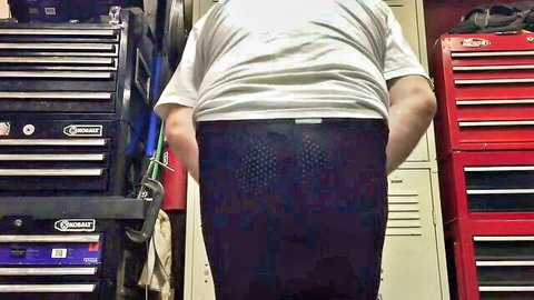 Man in white t-shirt and padded black shorts from behind in workshop