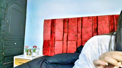 Long-haired Asian babe teasing on red velvet bed in off-shoulder white top