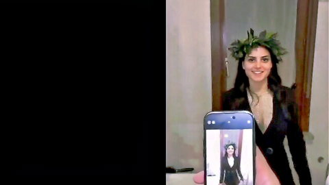 Busty brunette with deep cleavage in low-cut dress smiling selfie holding phone