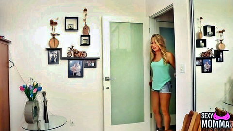 Blonde Tara Holiday in teal tank top and denim shorts in seductive pose