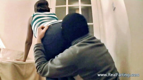 Curvy black woman in striped top bent over as masked man grabs her big ass in fart fetish scene
