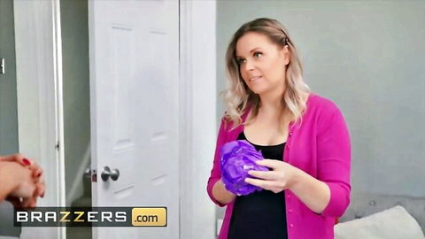 Curvy blonde MILF in pink cardigan holding big purple dildo smiling teasingly