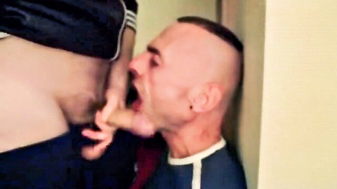 Bald man kneels to perform intense oral sex on standing partner's exposed genitals