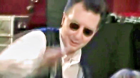 Close-up of smiling man in sunglasses white shirt and dark vest in red room