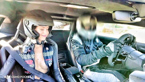 Busty babe exposes huge bare tits in open checkered racing suit inside sports car with helmeted driver