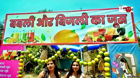 Two smiling Indian teens Babli and Bijli posing at juicy fruit stall with pineapples and oranges