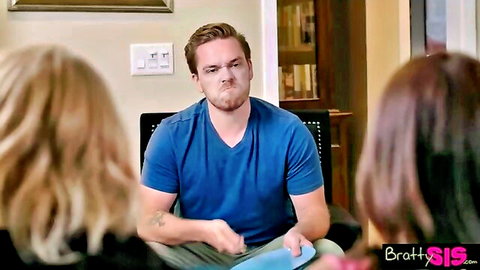 Shocked guy in blue shirt grimaces holding plate as two women confront him in living room
