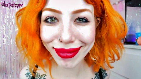 Freckled redhead smiling with deep cleavage and tattoos in low-cut black top selfie