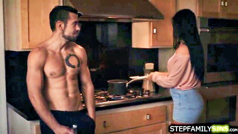 Jennifer White as brunette stepmom in kitchen with muscular stepson
