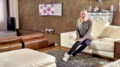 Skinny blonde MILF in gray sweater spreads legs teasingly on white couch smiling seductively