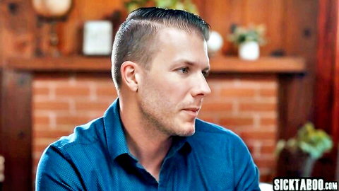 Handsome white guy with slicked undercut hair in blue shirt profiled by cozy fireplace