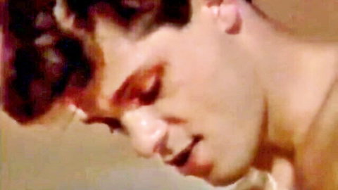 Vintage 80s gay porn thumbnail: young man with curly hair in close-up erotic gaze