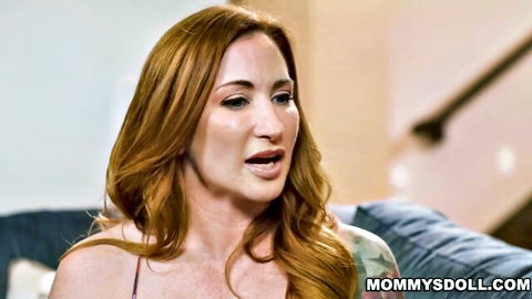 Redhead MILF with big tits teasing cleavage in low-cut top on couch