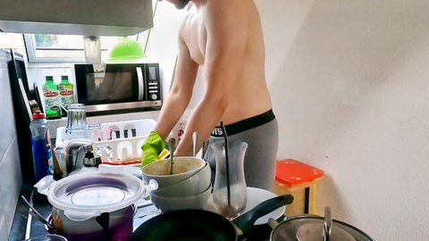 Muscular shirtless guy in tight gray Levi's briefs washes dishes in kitchen wearing green gloves