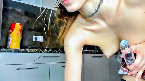 Topless petite brunette with small natural tits holds oil bottle in kitchen wearing plaid skirt and stockings