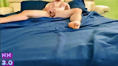 Young naked guy spreads legs holding his hard cock on blue bed