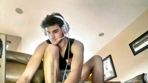Handsome black-haired college guy in tank top and headphones, amateur gay webcam pose