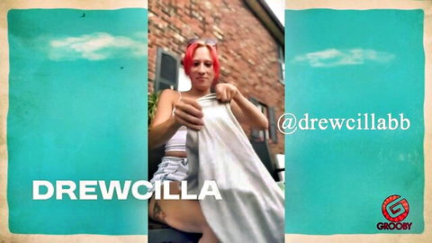 Redhead Drew C Willilla in crop top and shorts, holding sheet outdoors