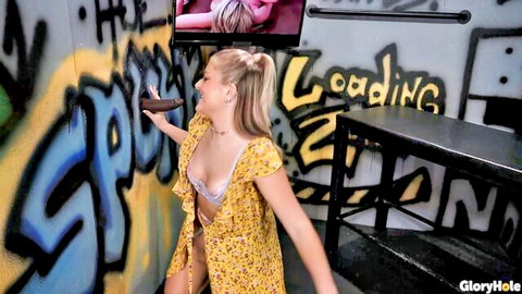 Blonde Jill Taylor in open yellow dress teasing at gloryhole with dildo