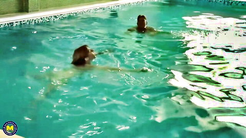 Two busty mature women skinny dipping nude in turquoise pool water