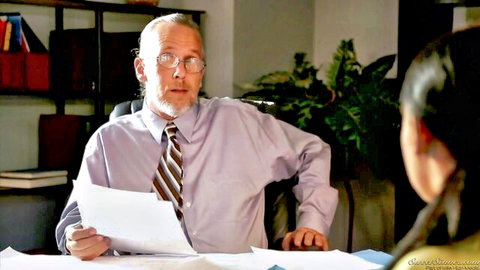 Katie St Ives in office scene with older suited man holding papers