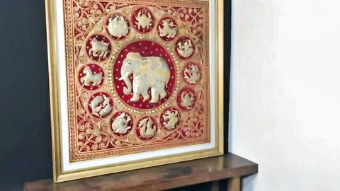 Ornate gold-framed red artwork with central white elephant surrounded by zodiac animals on shelf