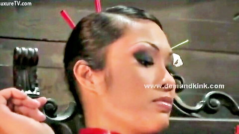 Asian dominatrix in red outfit with chopstick hair, intense gaze for BDSM kink