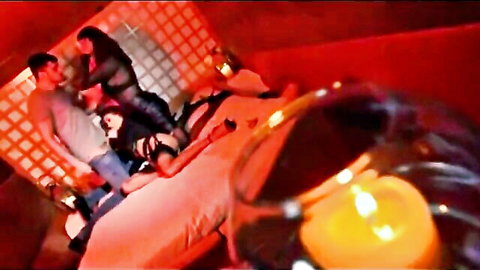 Sultry lesbian group scene with women in lingerie on bed, red-lit passion