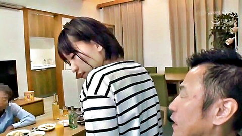 Japanese woman in striped sweater smiles teasingly at man sitting at kitchen table