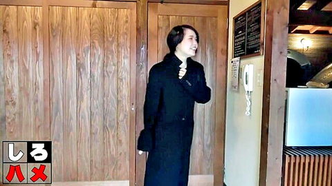 Smiling Japanese woman in long black coat using intercom at door