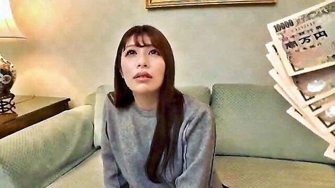 Sexy Asian woman in gray sweater sitting on couch with stack of yen cash
