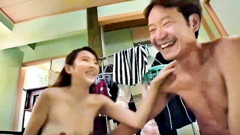 Topless Japanese teen babe with perky tits laughs while touching naked older man's chest