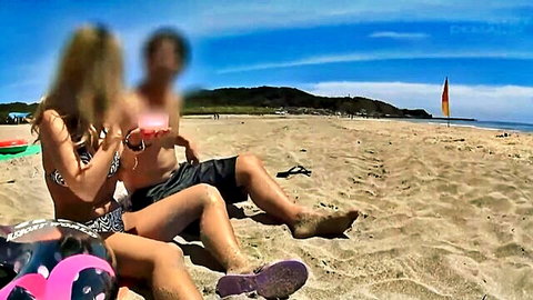 Busty Japanese woman in skimpy bikini lounging on sunny beach with partner