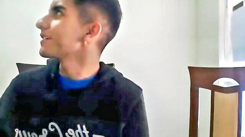 Young man with short dark hair and earring in black hoodie, webcam profile view