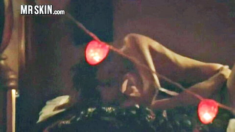 Nude woman lying seductively on bed under red lights