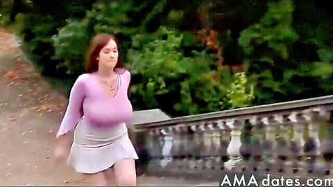 Curvy redhead in low-cut purple top and white mini skirt walking outdoors
