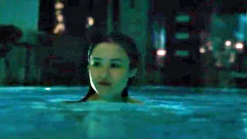 Young Asian beauty submerged in glowing blue pool water at night, teasing underwater nude scene