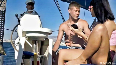 Brunette babe with small tits and long hair flirts intimately with shirtless guy holding phone on sunny boat