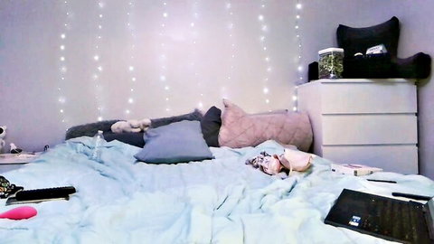 Pink dildo on messy blue bed in amateur webcam bedroom with fairy lights and stuffed toys