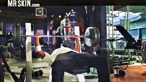 Sweaty muscular black man bench pressing weights in intense gym workout