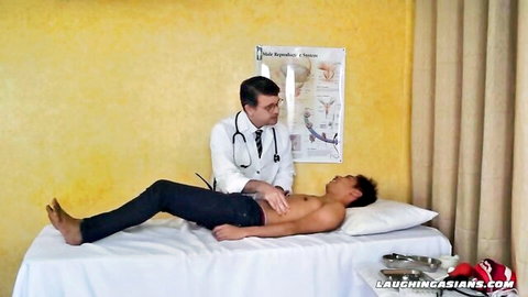 Gay doctor examines shirtless East Asian hunk's bare chest in medical fetish exam