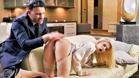 Suited man grabs blonde's exposed ass and pussy from behind on couch