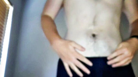 Shirtless slim man with hands near crotch in teasing pose, panties nuzzling fetish tease