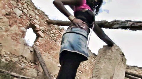 Sexy ebony babe in tight short denim skirt and stockings posing outdoors in stone ruins